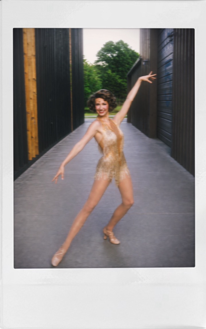 A polaroid of Beth Anderson in a gold fringed costume, one arm lifted and a leg extended, posing in a breezeway
