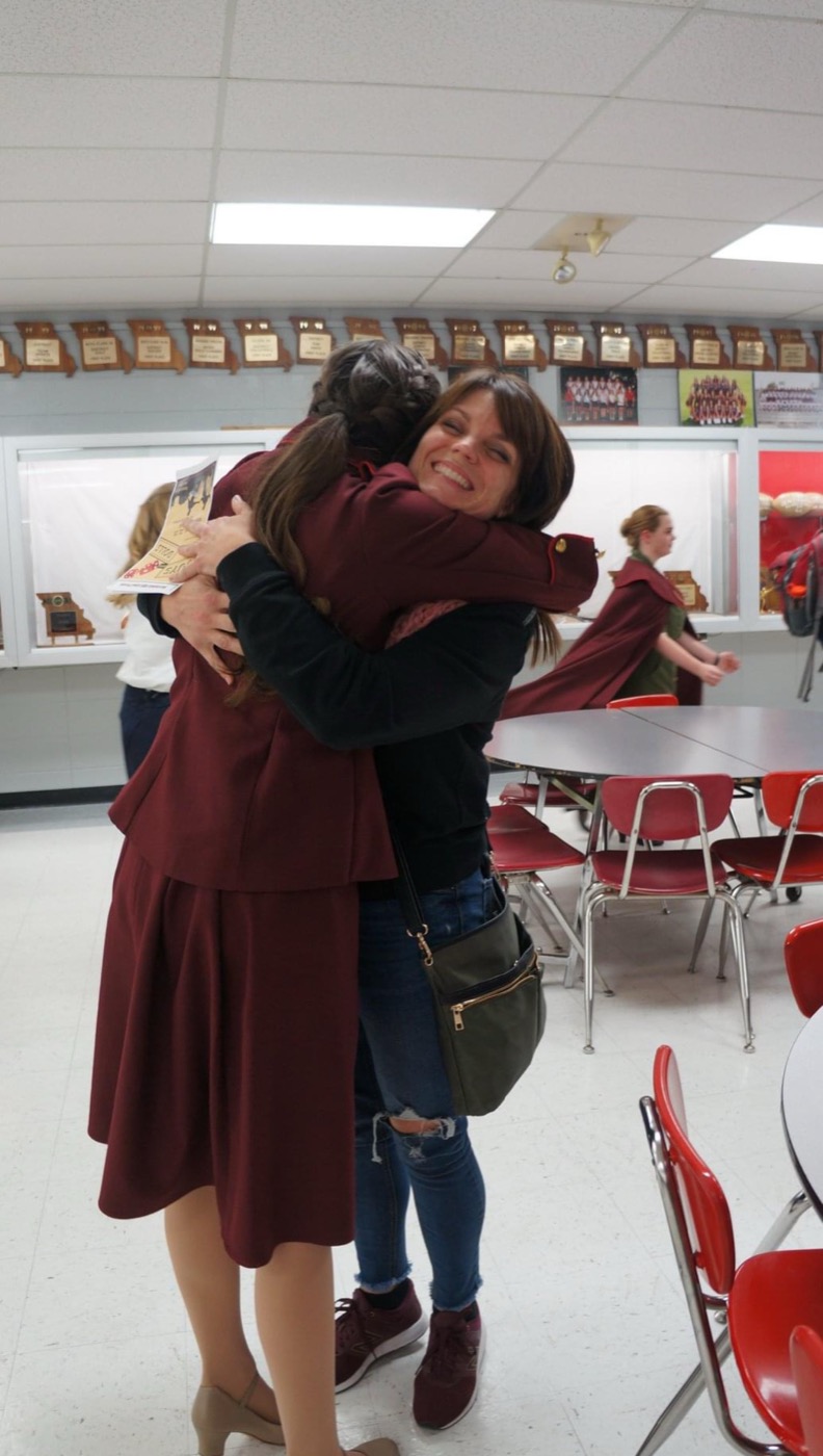 Beth Anderson in her maroon Guys and Dolls costume, hugging her longtime mentor Jennifer Renfrow, artistic director of Center Stage Academy of the Performing Arts